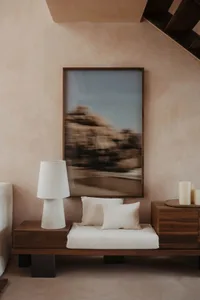 Cozy bedroom with a large mirror above a bench, pillows, and two lamps creating a warm and inviting atmosphere