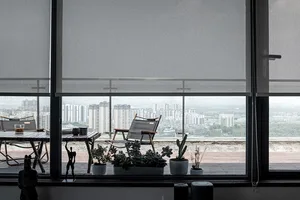 Cozy indoor living area with a large window offering a city view, potted plants, and a chair for seating