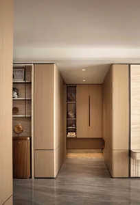 A wooden cabinet with a brown door in a residential hallway, surrounded by other doors and decorative items