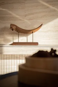 A wooden bull sculpture on a pedestal in a museum or gallery, surrounded by an atmosphere of art and creativity