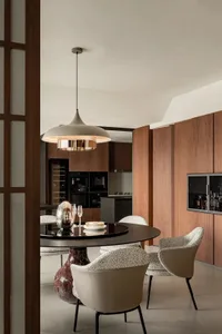 Warm and inviting open concept dining space with a dining table, chairs, and a kitchenette, featuring a wooden floor and warm lighting