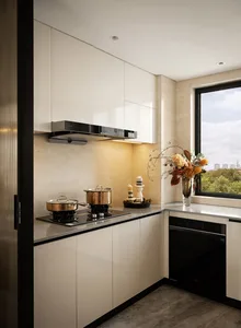 A well-organized kitchen with white cabinets, two sinks, and natural light from a large window, featuring various kitchen items and potted plants