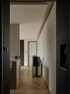 Empty living room with a black TV on a stand in front of a white wall, two chairs placed near the TV, giving off a calm and serene atmosphere