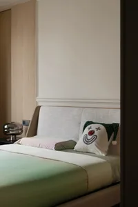 Cozy bedroom with a large bed on a green carpet, a chair, and a bed with a white comforter and a smiley face pillow