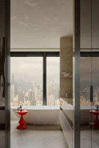 Bathroom with a bathtub and potted plants near a large window overlooking the city skyline