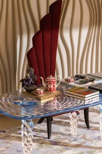 A comfortable living space with a glass coffee table, red chairs, books, cups, and a vase, creating a sophisticated ambiance with modern touches