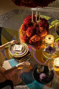 A dining table set with a red flower centerpiece, wine glasses, books, and fine china in a luxurious restaurant setting