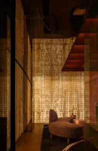 Cozy living area with a couch and two chairs, dimly lit with wood and stone wall features
