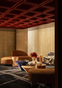A living area with two couches, three chairs, and red panel walls, creating a warm and inviting atmosphere with a wooden theme