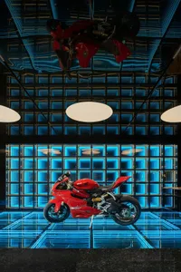 A modern showroom featuring a red motorcycle on display, surrounded by blue walls and a stylish atmosphere