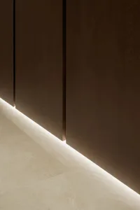 A room with a brown wooden wall, two doors, and a light shining through one of them, creating an interesting effect