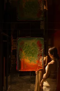 A woman admires artwork in a gallery with mirrored display cases and modern art pieces with vibrant colors and unique designs