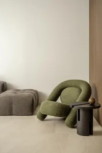 Cozy living space with a green couch, a grey couch, three chairs, and a dining table in front of a white wall