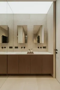 A clean and well-organized bathroom with two sinks under mirrors, wooden cabinets, and countertops, featuring toiletries and personal care items