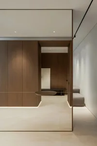Empty room with wooden walls and floors, featuring two couches and a chair, well-lit with natural or artificial light