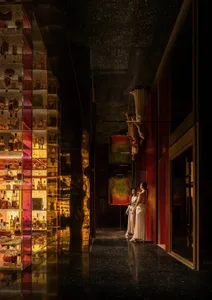 A woman stands in front of a large mirror in a luxurious room with a black and gold theme, surrounded by bottles and vases