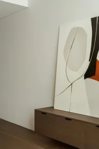 A calm and inviting room with a large abstract art piece on display, set against a wooden-framed wall