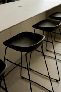 Empty kitchen space with four black stools around a marble countertop island, creating a casual dining atmosphere
