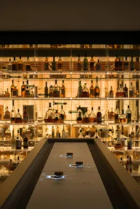 A bar filled with bottles of alcohol and wine glasses on a countertop, conveying elegance and a wide selection of drinks