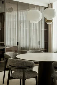 A modern dining area with a round glass table surrounded by chairs, creating a comfortable seating arrangement for guests
