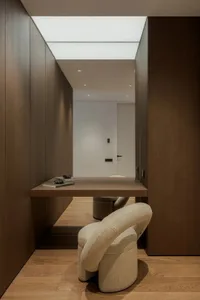 Cozy modern living space with brown wood furniture, white cushions, and a dining table, creating a warm and inviting atmosphere