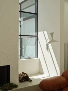A modern living area with two couches, a chair, and a large window allowing sunlight to stream in