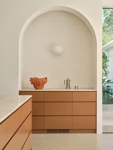 A kitchen with brown cabinets, white walls, two sinks, and a vase on the countertop, showcasing a clean and organized space with a focus on functionality and aesthetics
