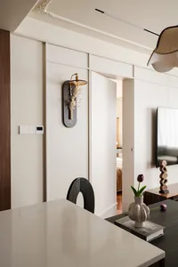 A cozy dining area with a wooden table and chairs, a vase on the table, and a TV mounted on the wall