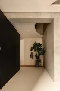 A simple hallway with a door on one side, a wall on the other, and two potted plants with a vase between them