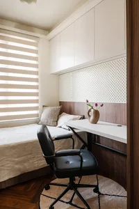A bedroom with a wooden theme, featuring a bed, desk, chair, and vase of flowers, with a warm and cozy atmosphere