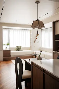 Open concept living area with white walls, wooden floors, two couches, a chair, potted plants, and decorative vases