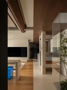 Open living area with wooden floors and walls, featuring a TV, couches, and potted plants