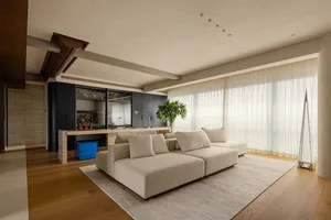 Open living area with a couch, chairs, dining table, and a potted plant, featuring a flat screen TV and natural light