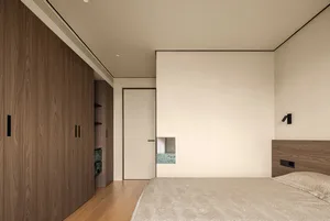 Empty minimalist bedroom with a large white wall, wooden floor, and two doors leading to other areas of the house