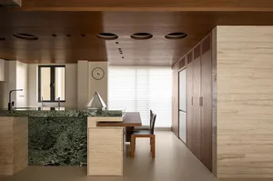 Modern kitchen and dining area with marble countertop, clock, and dining table with chairs