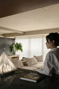 A well-lit living area with a couch, chair, and potted plant, designed for relaxation and socializing