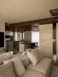 Open living area with white walls, wooden floors, two couches, a chair, and a clock on the dining table, with bright and inviting atmosphere and natural light