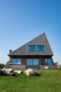 Modern house with a triangular shape, wooden exterior, and multiple windows providing natural light