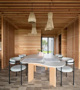 Cozy living area with a wooden dining table and four chairs, surrounded by natural materials and comfortable seating options