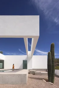 A modern house with a white exterior, concrete walls, and a pool, featuring outdoor furniture and a cactus, set in a calm and inviting atmosphere