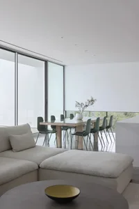 Open modern living space with a glass wall, wooden dining table, and comfortable seating for guests