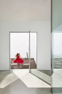 A young girl in a red dress spins around in a room with hardwood floors, two doors, and three bowls, creating a playful and joyful atmosphere