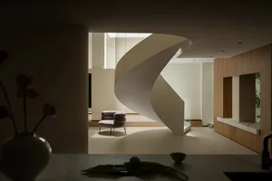 Modern living space with a spiral staircase made of wood, a chair, and a vase, set against a neutral background