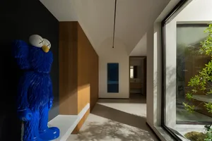 A warm and inviting living space with a blue Elmo doll on a white counter, wooden floors, and a dining table near the left wall
