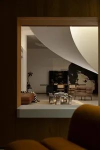 Cozy modern living area with a couch, chair, coffee table, and TV, dimly lit with two potted plants