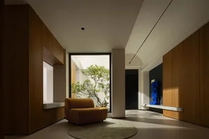 A bright and inviting living area with a large window, two chairs, a couch, and a potted plant, creating a comfortable and relaxing atmosphere