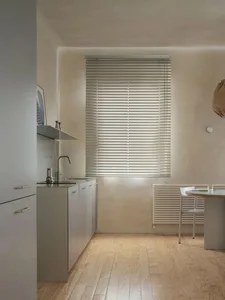 Modern kitchen and dining area with white walls, a table, chairs, and natural light from a window