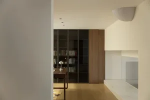 A warm and inviting living space with wooden floors, white walls, bookshelves, a dining table, and a chair, perfect for relaxation and socializing