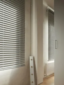 Interior room with white blinds, natural light, and a wall-mounted air conditioner unit