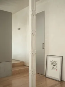 Clean and organized interior hallway with a white door, staircase, and framed artwork on the walls